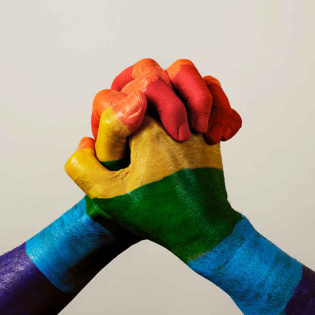 picture representing the glbtqi+ community with rainbow painted hands joining together